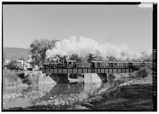 View of Locomotive No. 12 about a quarter mile north of Orbisonia, crossing steel I-beam plate girder bridge after clearing yard at Orbisonia - East Broad Top Railroad